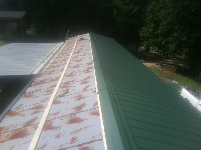 Old rusted panels beside newly installed green metal roofing — Wind Damage Roof Repair by Roofing Brothers in Wadena