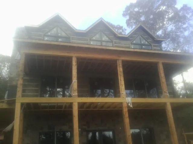 Dormers and porch framing on a large log home under construction — Roof Coating work by our crew in Wadena