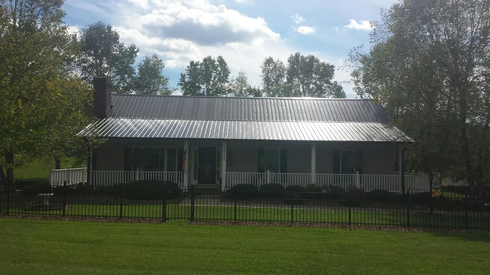 Gray metal roof on a brick ranch with a full width front porch — Gutter Guard Installation work by our crew in Wadena